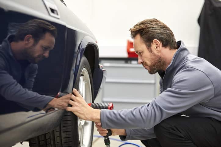 Engineer using electric impact wrench on car wheel