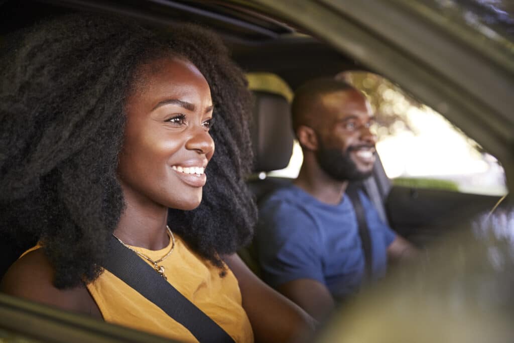 Young black couple smiling in a car during a road trip