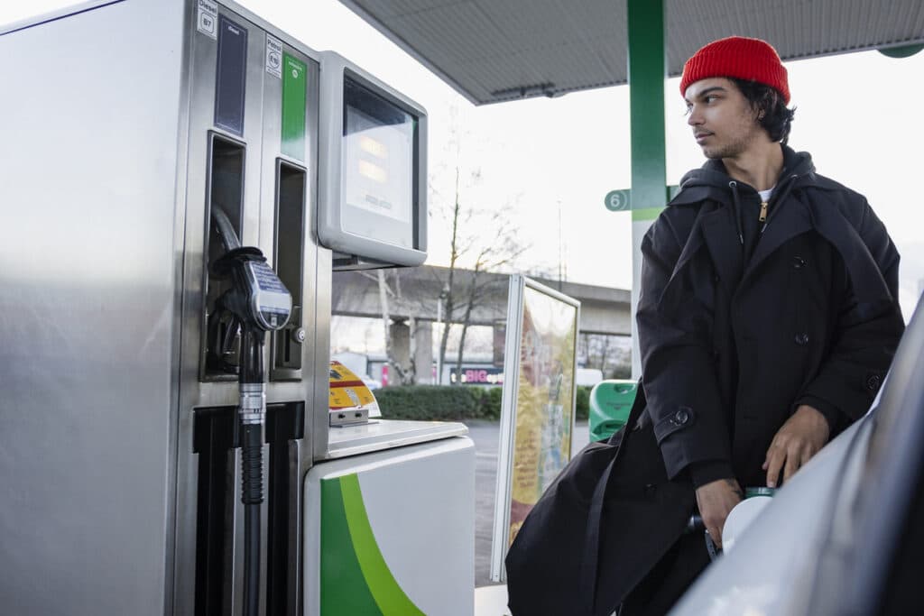 Man putting fuel into his car while shoppers at a garage in the North East of England.