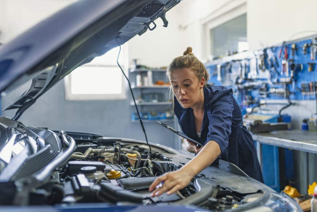 female mechanic reaching into car fixing an issue