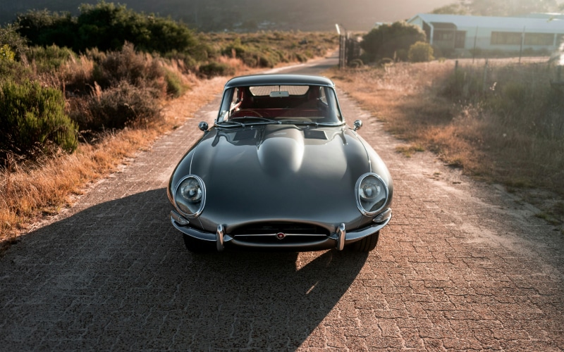 empty grey classic car by itself on a paved road.